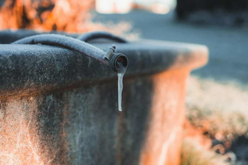 An icicle hanging from an outdoor water spout on a frosty morning